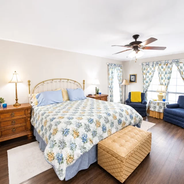 Master bedroom with brass bed frame, floral bedding, and navy chairs by windows, a best hikes near Georgetown, TX stay at
