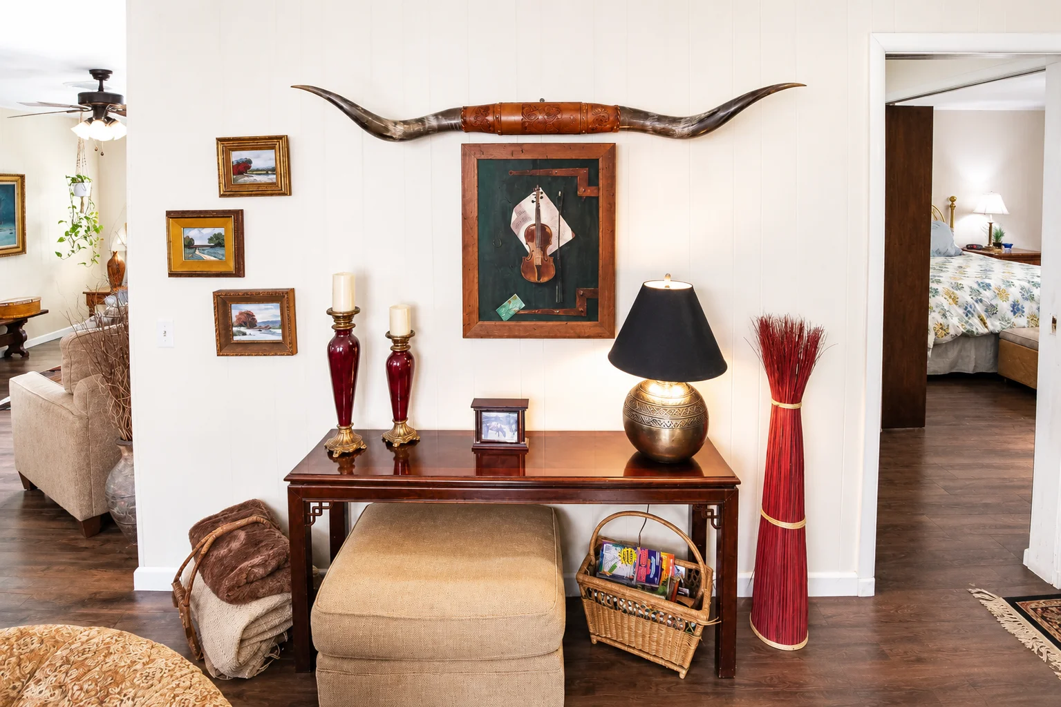 Living room with dark wood console table, brass candlesticks, globe lamp, and longhorn mount, styled Western decor at our