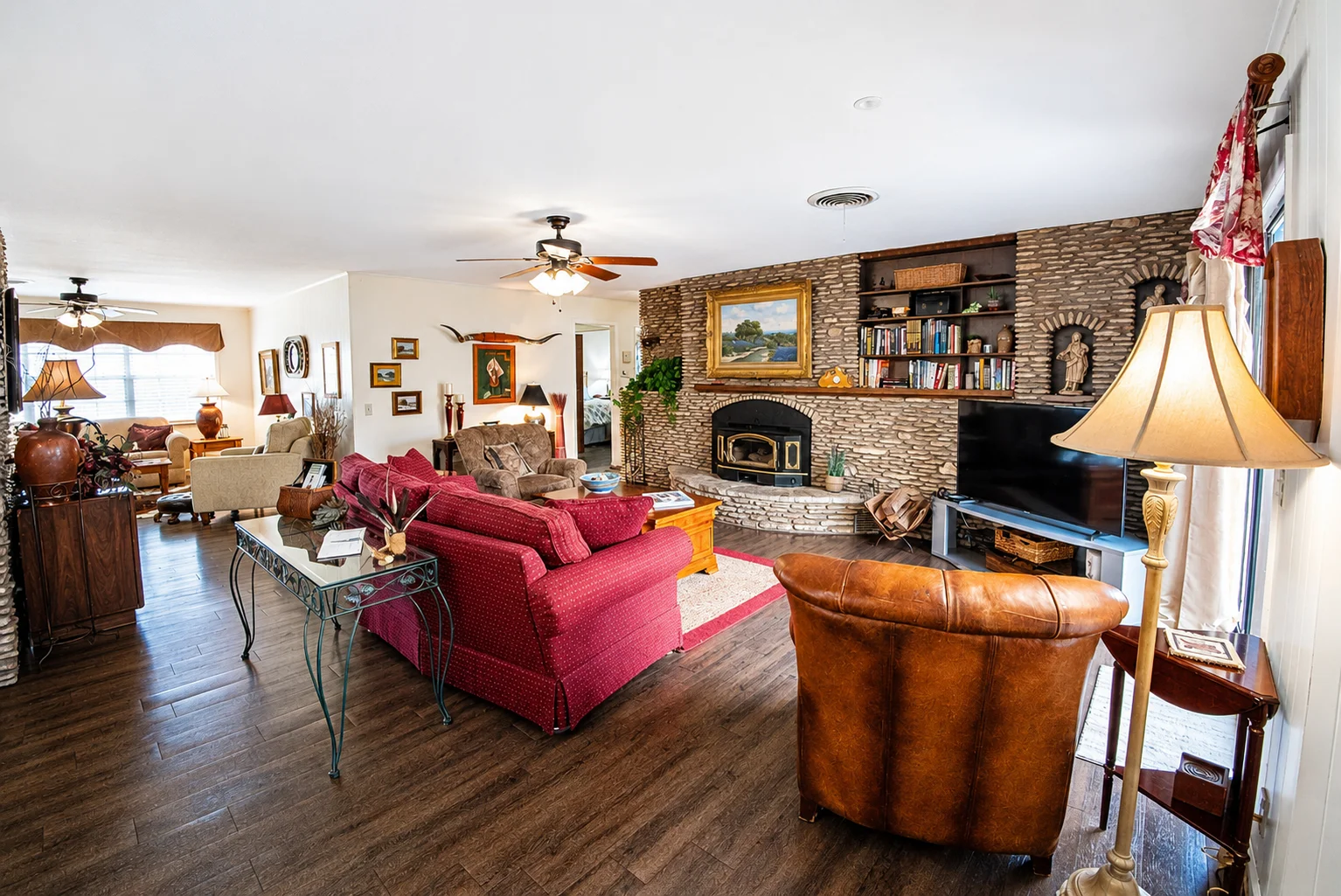 Rustic living room with stone fireplace and burgundy sofa at Scurlock Farms near Georgetown Texas
