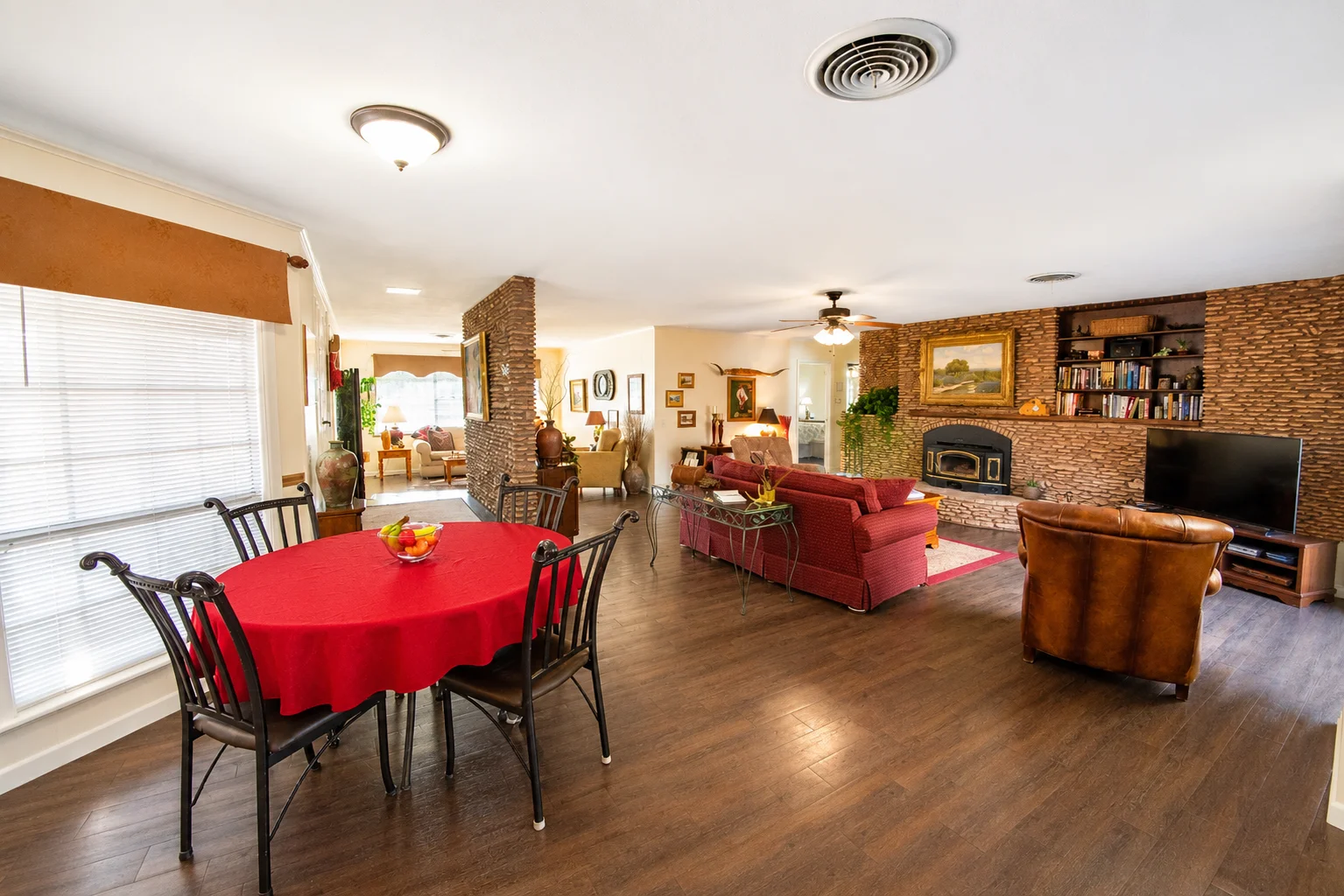 Open-concept living and dining area with brick fireplace and round table at Scurlock Farms Georgetown TX