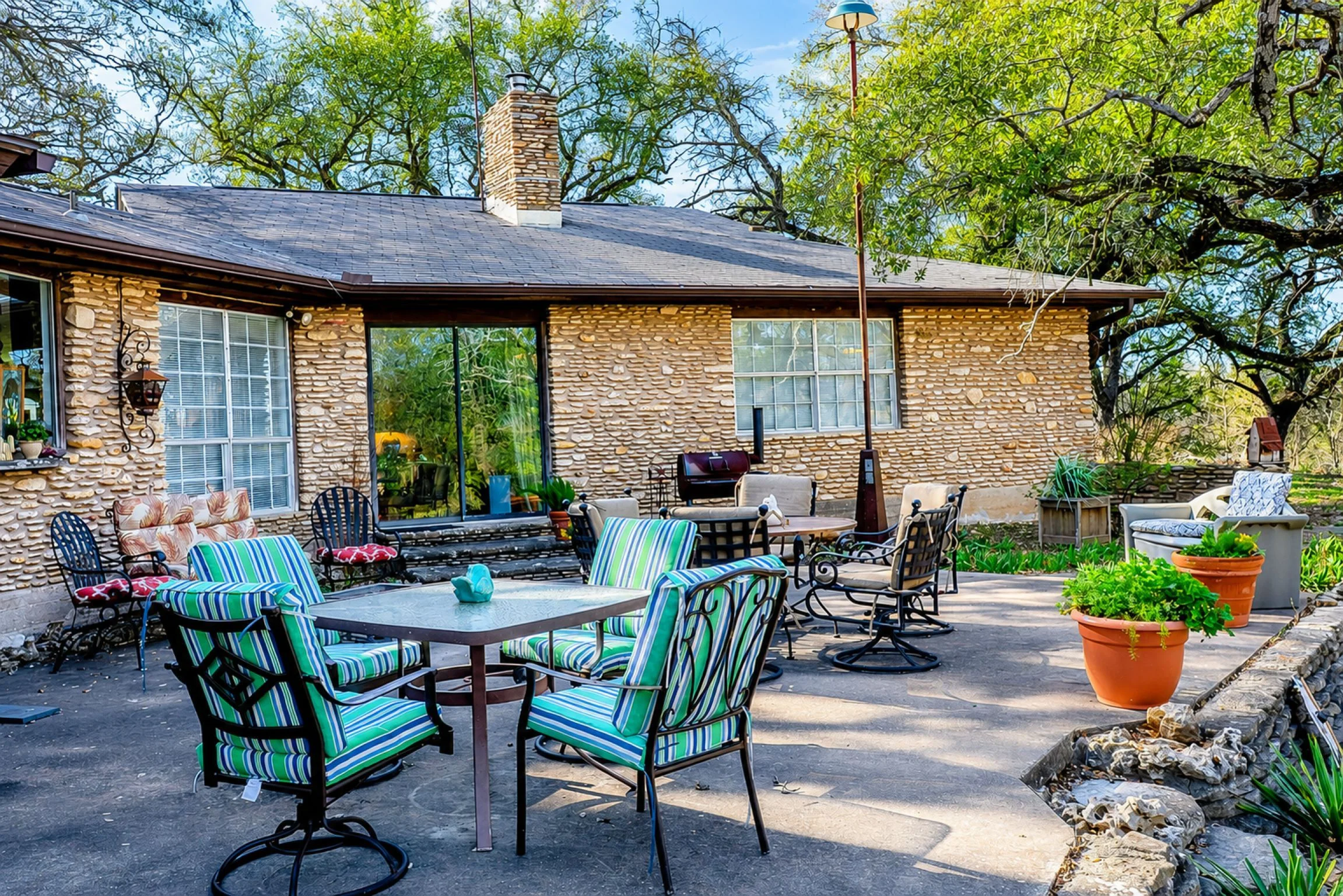 Outdoor patio dining seating with striped chairs and stone table at Scurlock Farms Georgetown TX